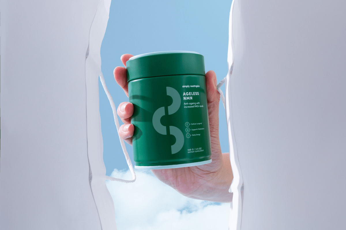 A hand holding a green Ageless NMN supplement container.
