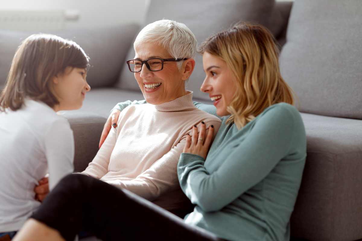 Three generations of women laughing together at home.