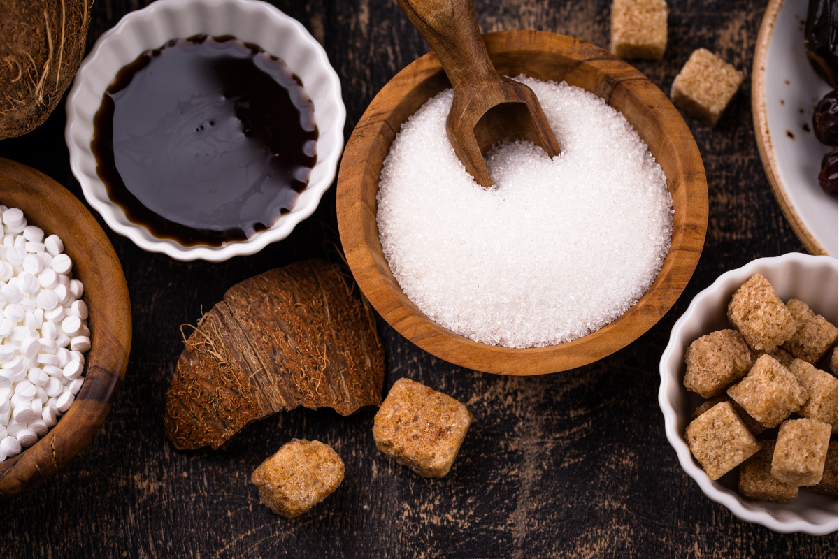 Various types of sugar in bowls on rustic wooden table with coconut shell.