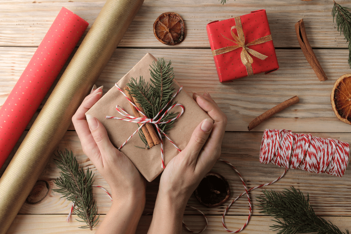 Hands holding a holiday gift on a wooden table.