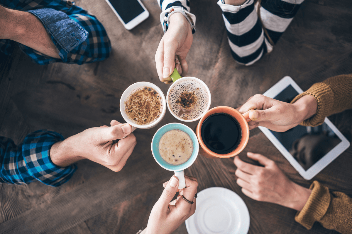 Group of people holding coffee cups together.