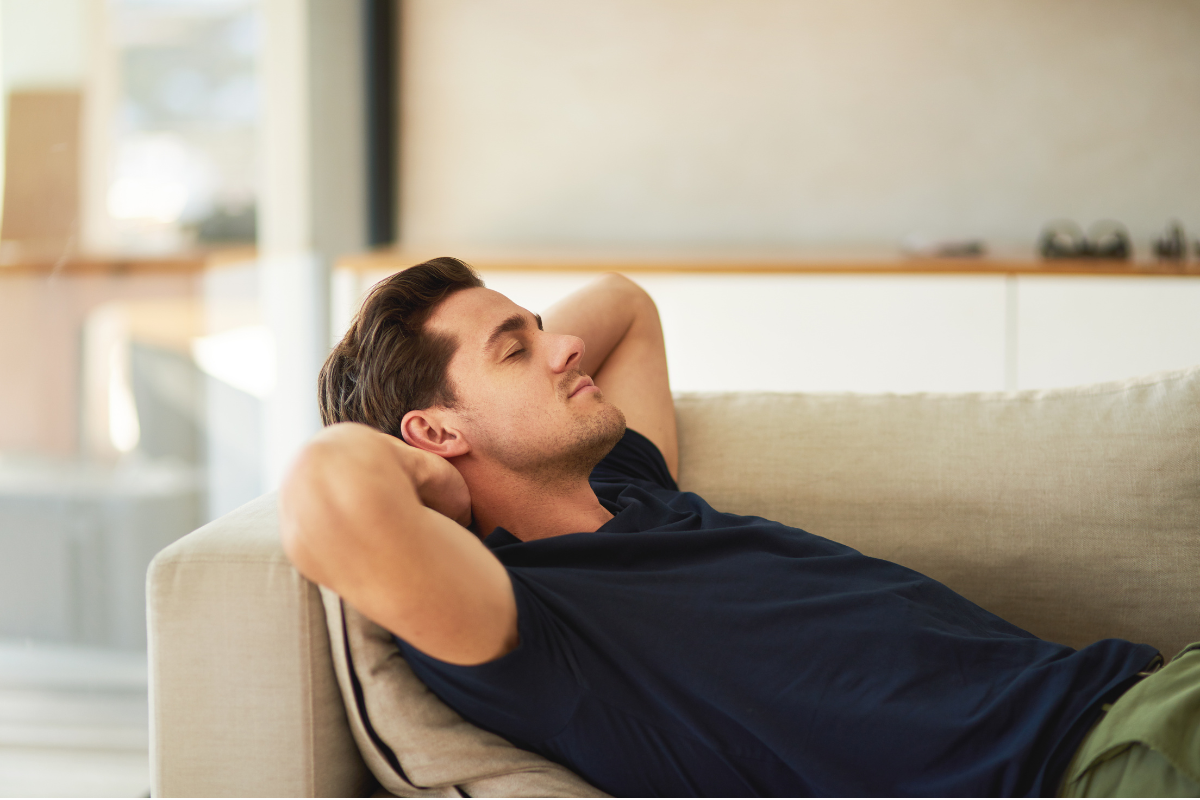 Man relaxing with his eyes closed on a sofa.