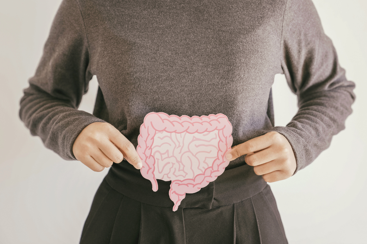Person pointing to illustrated gut over abdomen to represent digestive health.