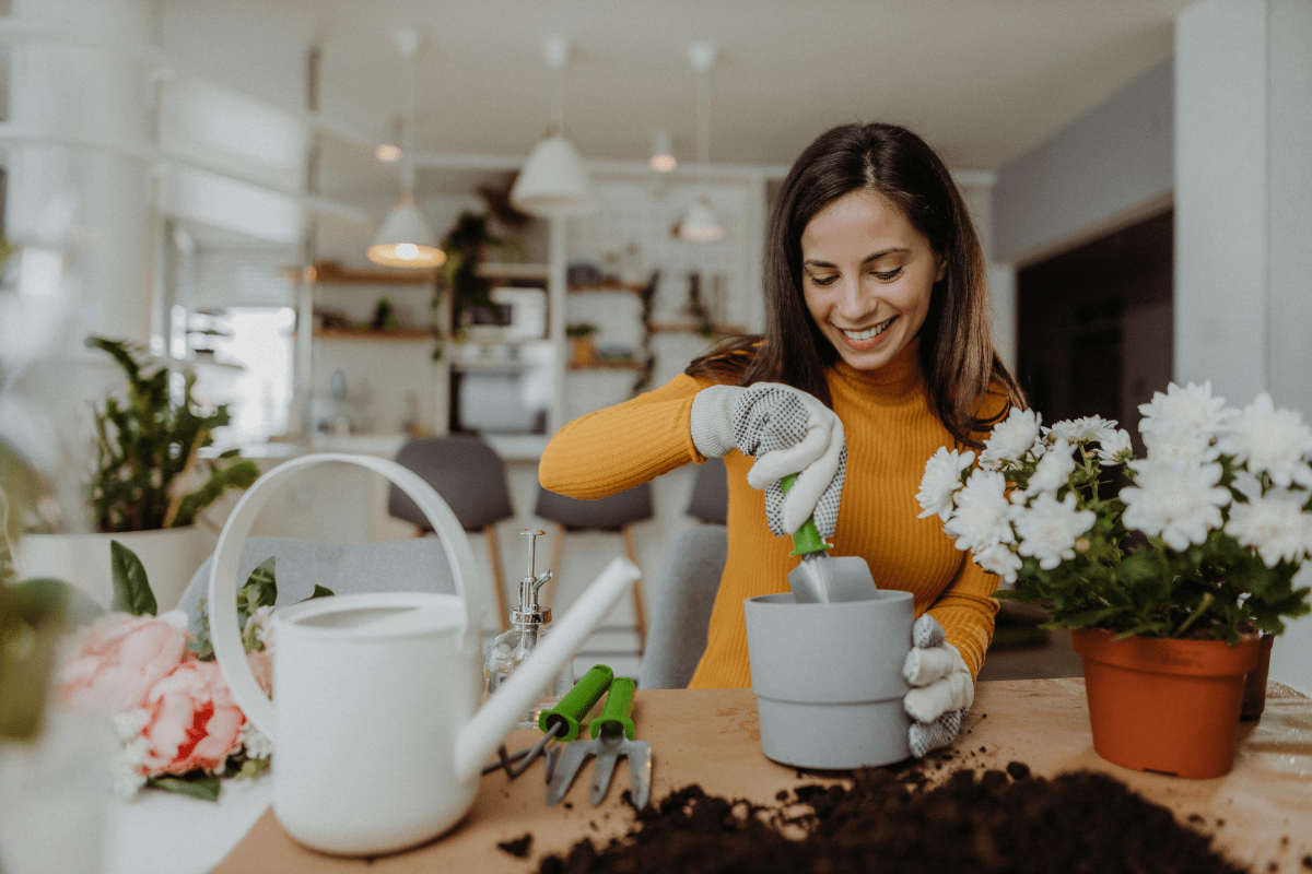 Smiling woman potting a plant indoors.