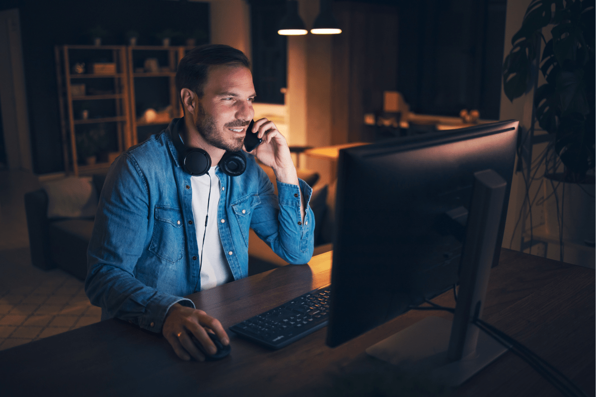 Man working late at a computer with headphones around his neck.