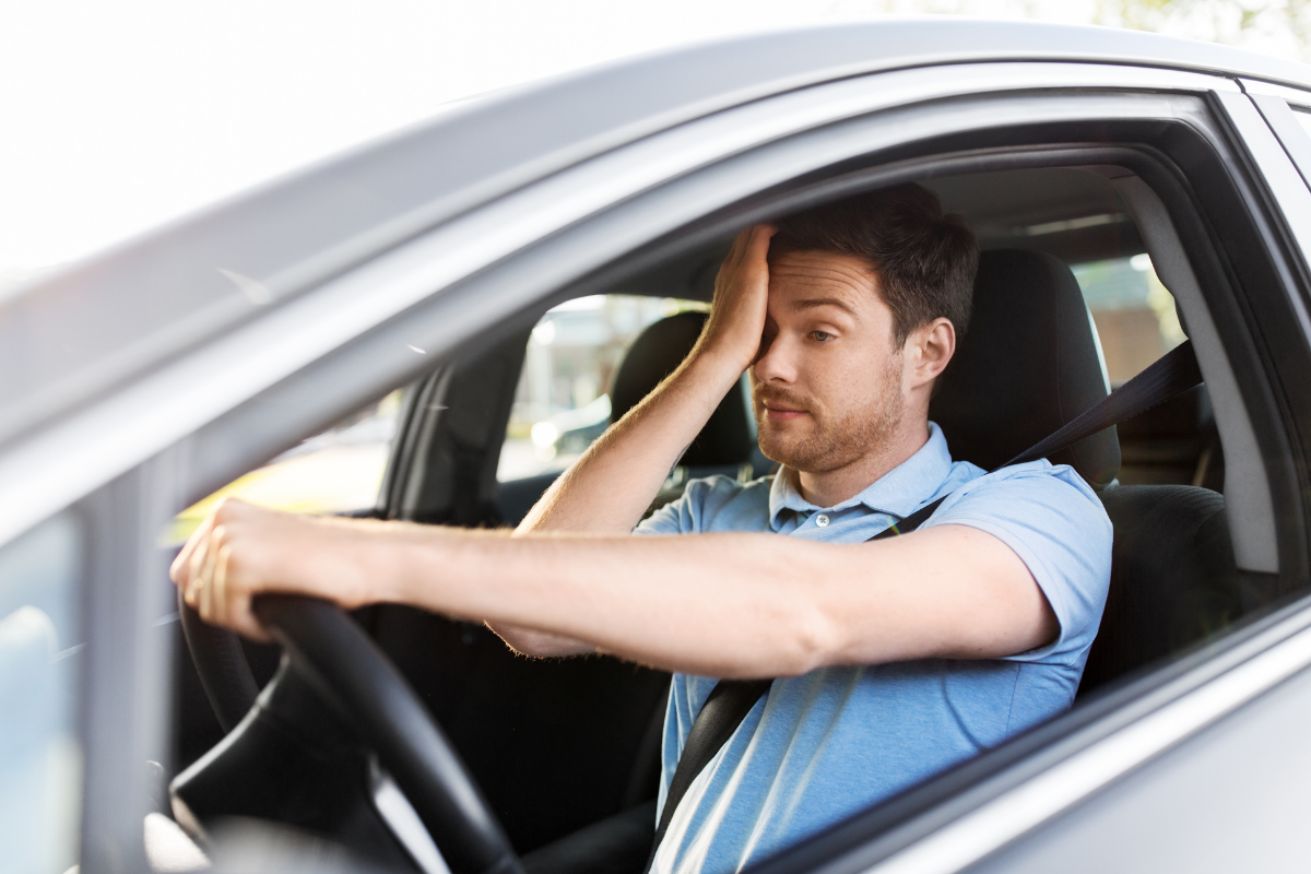 Tired man struggling to stay awake while driving.
