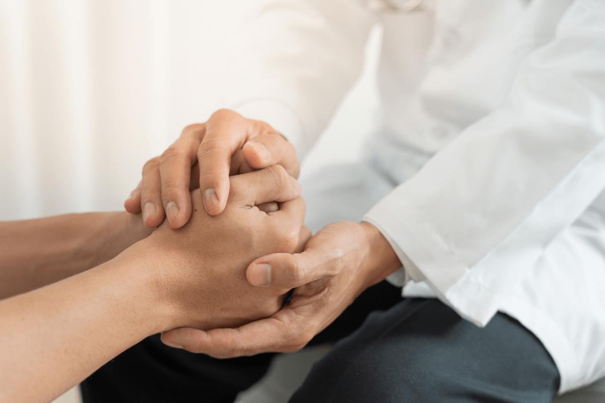 A healthcare professional holding a patient's hands.