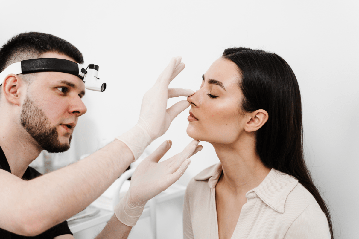 Doctor examining a woman's nose during a nasal health consultation.
