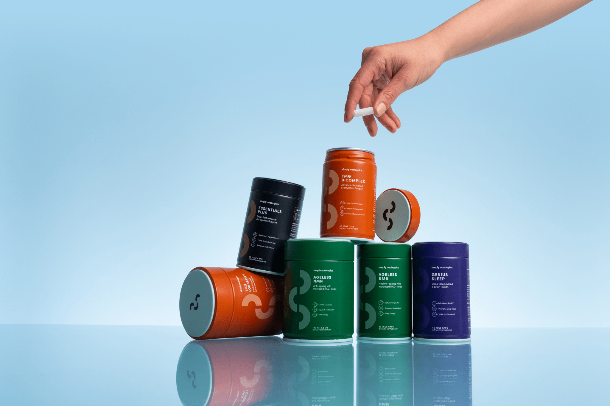 A hand picks up a capsule from a balanced stack of Simply Nootropics supplement containers.