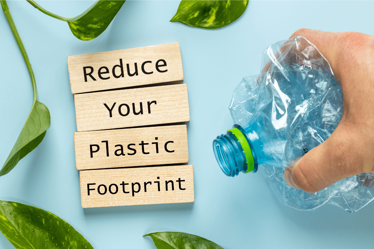 A hand crushes a clear plastic bottle next to wooden blocks spelling out 