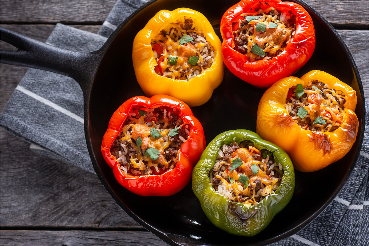 Colourful stuffed bell peppers filled with rice and ground meat in a skillet.