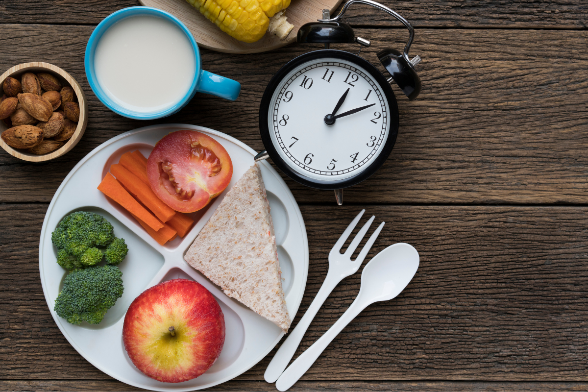 A plate of healthy food and a clock, symbolising meal timing for health.