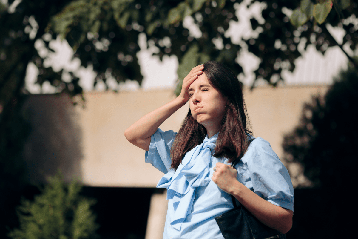 Woman outdoors holding her head in frustration.
