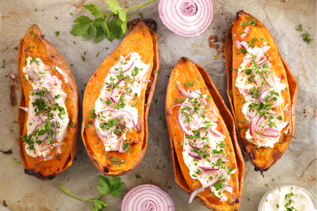 Baked sweet potatoes topped with sour cream, red onion, and herbs.