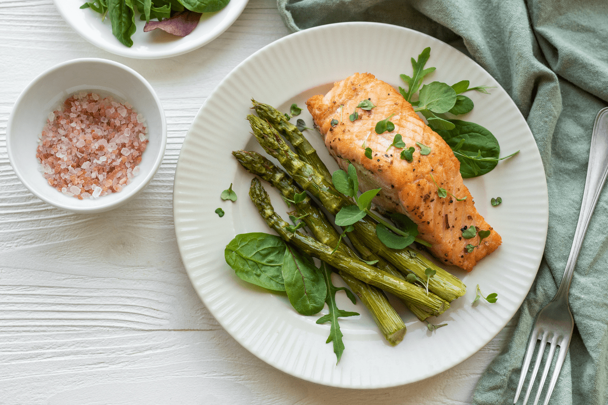 Grilled salmon served with roasted asparagus on a white plate.