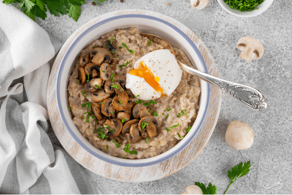 Bowl of savoury oats topped with sautéed mushrooms and a poached egg.