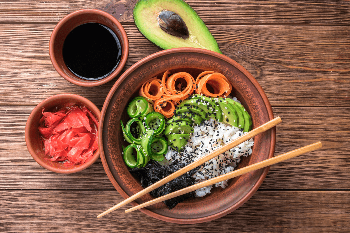 A vibrant sushi bowl accompanied by bowls of soy sauce and pickled ginger.