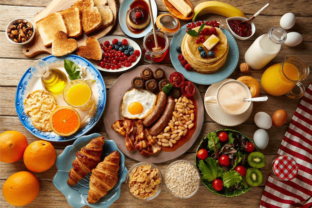 A variety of breakfast foods arranged on a rustic wooden table.